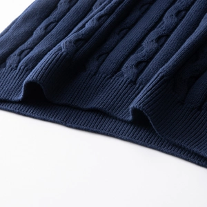 Detail of navy blue cable knit pattern and ribbed hem on a men's cotton sweater