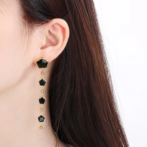 Close-up of elegant long tassel earrings with five black star gemstones in gold finish