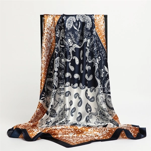 Detail view of large paisley silk scarf with contrast borders draped on a black stand