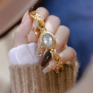 Detailed close-up of a gold-tone tiger eye stone watch on a woman's wrist