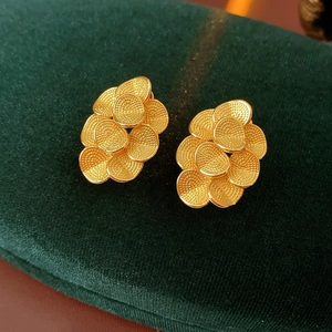Vue macro de boucles d'oreilles fleurs plaquées or 18K avec texture mate sur velours