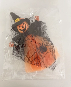 Close-up of a Halloween witch doll with orange pumpkin head and black mesh spider web dress
