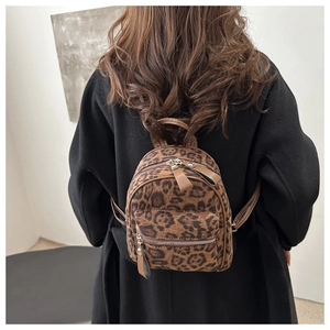 Detailansicht Mini-Rucksack mit Leopardenmuster und braunen Lederriemen auf schwarzem Mantel