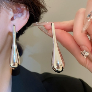 Macro shot of large silver teardrop earrings featuring a polished mirror finish on metal