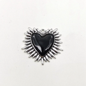 Macro detail of gothic sacred heart pendant with silver metal rays and black enamel inlay