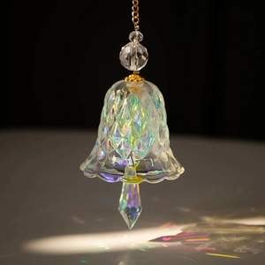 Close-up of diamond-cut rainbow crystal bell with gold hanging chain and faceted drop pendant