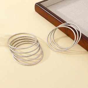Detailed view of layered 3mm silver stainless steel bangles on dark wood tray