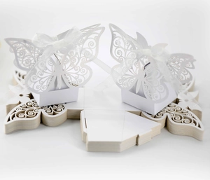 Detail of white laser-cut butterfly favor boxes with elegant ribbons and flat packaging