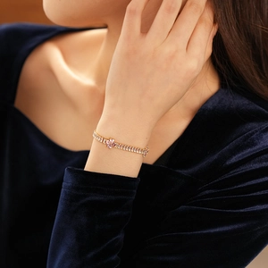 Detail of gold bracelet with pink zircon flower and clear crystals on a model wrist