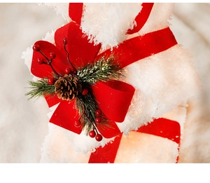 Macro view of white snow-texture Christmas gift box with red ribbon and warm LED lights
