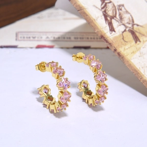 Macro detail of gold C-shaped hoop earrings with square-cut pink zircon stones