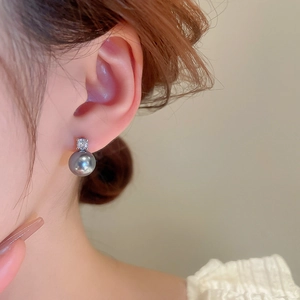 Detail of silver earring featuring a lustrous grey pearl and a sparkling zircon stud