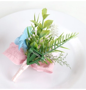 Detail of blue and white wedding boutonniere with green leaves and pink ribbon