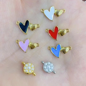 Macro view of multi-color enamel double heart pendants and pearl connectors on hand