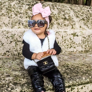 Outdoor street style shot of kids fashion accessories including bow headband and quilted bag