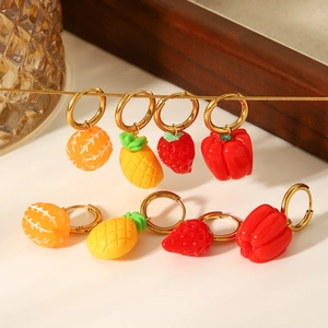Golden stainless steel hoop earrings with colorful fruit resin pendants shown on tray