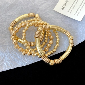 Detail view of four-piece gold bracelet set with smooth beads and spiral metal tubes
