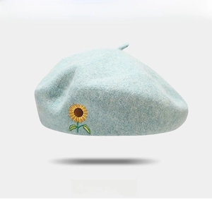 Close-up of sky blue wool beret featuring intricate sunflower embroidery and soft fabric