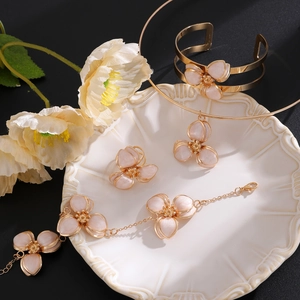 Nahaufnahme des goldenen Blumen-Schmucksets mit Emaille-Blüten auf einem Vintage-Tablett