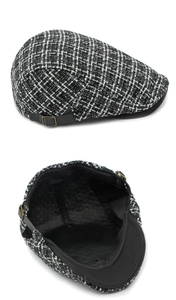 Detail van zwart-witte geruite tweed pet met lederen bandje en katoenen voering label