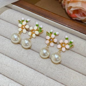 Nahaufnahme von Blumenperlen-Ohrringen mit Zirkonsteinen in Rosa und Beige