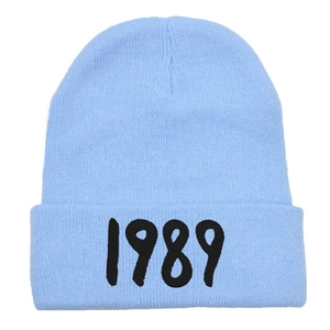 Detailed close-up of the black 1989 embroidery on a light blue knit beanie hat