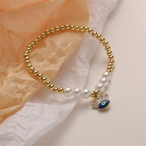 Dettaglio del bracciale con perle dorate e ciondolo occhio blu malvagio
