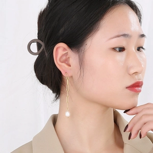 Détail de boucles d'oreilles vintage dorées à pampilles et perles sur un modèle