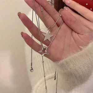 Detailed view of silver star necklaces featuring solid and hollow pendants on snake chains
