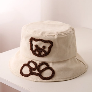 Vue détaillée de la broderie ours en 3D et de l'empreinte sur un chapeau beige