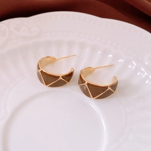 Detail of vintage geometric C-shaped earrings with gold and brown enamel texture