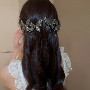 Detail of 3D rhinestone butterfly hair clips with tassels worn on wavy brown hair