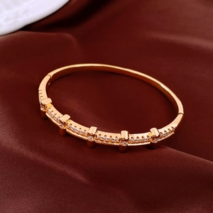 Vue détaillée du bracelet jonc plaqué or 18K avec zircons blancs sur satin marron luxueux