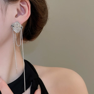 Macro shot of silver irregular textured square earrings with long tassels on a model