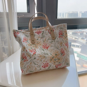Détail d'un sac cabas floral avec imprimé chrysanthème et poignées en cuir