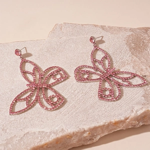 Detailed view of pink crystal butterfly earrings with sparkling stones on stone background