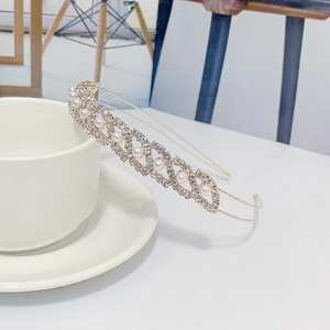 Detail of a gold headband with white pearls and rhinestones leaning on a tea cup