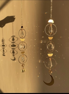 Set of two gold sun and moon crystal suncatchers casting rainbow light on a warm wall