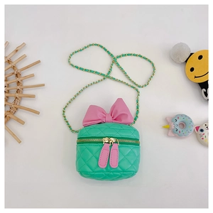 Detailed view of green quilted crossbody bag with a large pink bow and gold chain strap