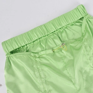 Detail of lime green satin trousers featuring elastic waistband and adjustable drawstring