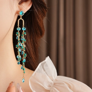Detail of long gold tassel earrings with blue crystals and turquoise beads worn by model