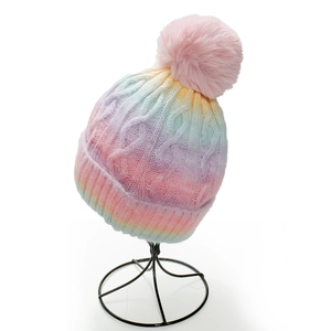 Detail of colorful gradient knit beanie with a fluffy pink pompom and cable knit texture