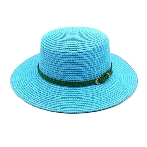 Détail d'un chapeau en paille bleu clair avec texture tressée et boucle en cuir vert foncé