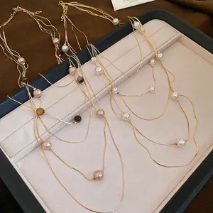 Multi-layer tiger eye and pearl gold necklace displayed in a jewelry box