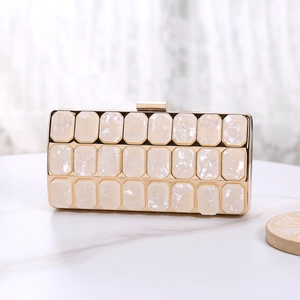 Detail of white pearlescent acrylic clutch with gold frame and square metal clasp