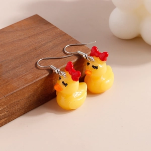 Cute yellow duck earrings with red bow and sunglasses on a wooden stand