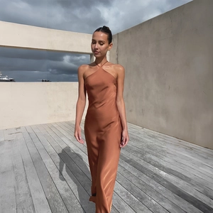 Detail of elegant caramel satin halter dress showing smooth texture and backless slim fit