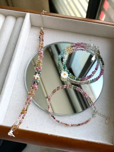 Detail of colorful gemstone beaded bracelets and necklaces with floral charms in a jewelry box