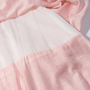 Détail de tissu superposé rose et blanc avec texture plissée sur une robe longue