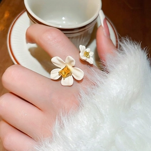 Gold plated open ring with double white flowers and yellow gemstones on hand